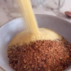 Mixing sweet and smokey BBQ rub ingredients in a glass bowl with wooden spoon