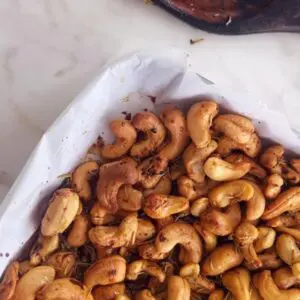 weet and spicy cashews on a lined baking sheet before roasting