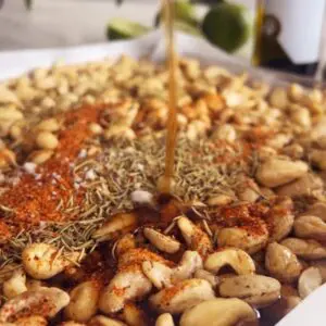 Sweet and spicy cashews on a lined baking sheet before roasting