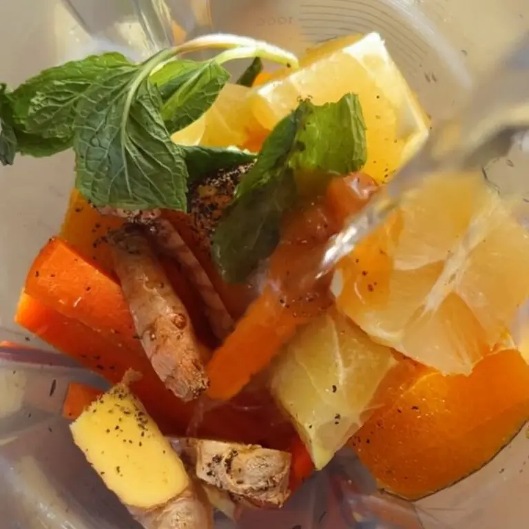 Fresh turmeric root, ginger, oranges, lemon, and carrots being prepped for adrenal immune wellness shots to support women's hormone health and HPA axis function