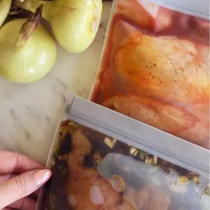 Five chicken marinades in labeled freezer bags with various herbs and spices for meal prep cooking