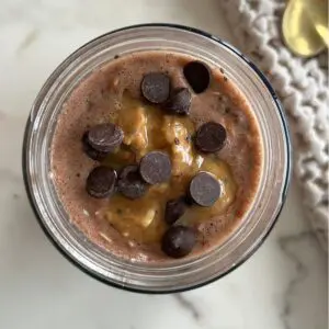 Mason jar filled with Peanut Butter Cup overnight oats with dark chocolate color and chocolate chips visible on top.