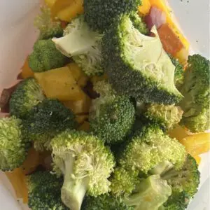 Reusable freezer bag with layered sausage bowl ingredients: gluten-free chicken sausages, diced sweet potatoes, bell peppers, broccoli, red onion, and Dijon honey mustard dressing