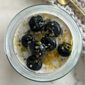 Mason jar filled with Lemon Blueberry overnight oats with fresh blueberries on top and lemon zest visible.