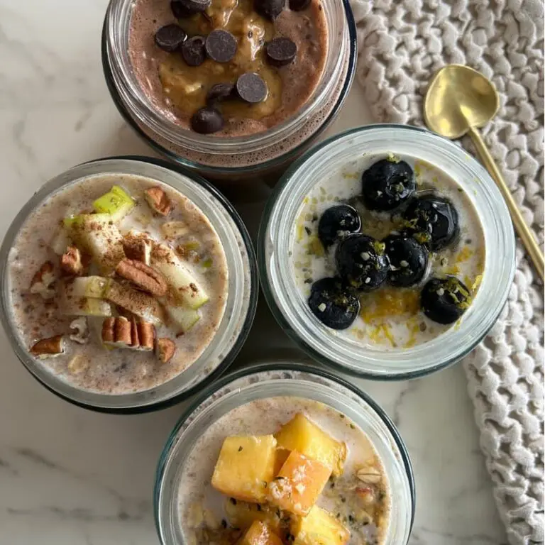 Four mason jars filled with overnight oats in four different flavors, each labeled with the flavor name and topped with fresh fruit and toppings.