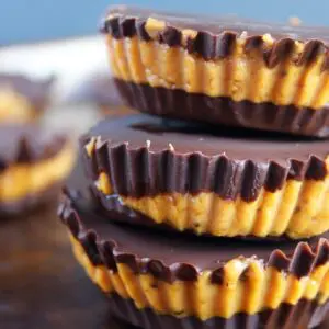 Melted dark chocolate being poured over frozen pumpkin peanut butter protein cups