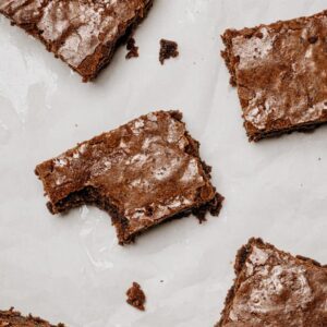 Stack of mocha fudge brownies made with chia seeds and Brazil nuts for perimenopause hormone support, garnished with chocolate chips and chopped nuts on white plate