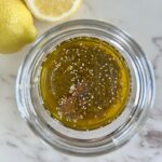 Mason jars filled with golden chia vinaigrette showing texture with swollen chia seeds