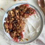 Close-up of granola bowl showing chia seed texture mixed with cookie pieces and berry compote