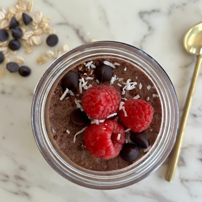 Ingredients for brownie batter chia overnight oats arranged on white background: rolled oats, chia seeds, raw cacao powder, regular milk, Greek yogurt, maple syrup, and dark chocolate chips