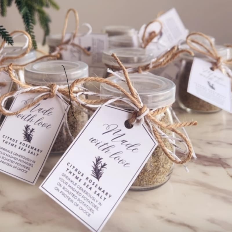 Small glass jars filled with golden citrus rosemary thyme sea salt with printable gift labels attached