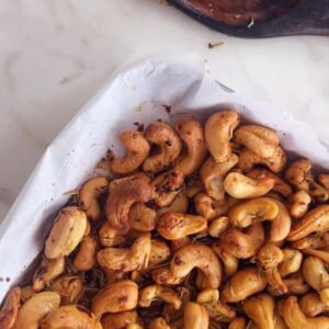 weet and spicy cashews on a lined baking sheet before roasting