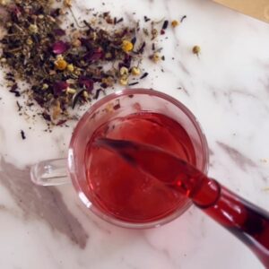 Dried herbs for sleepytime tea blend including chamomile, lavender, rose petals, hibiscus, and peppermint on white surface