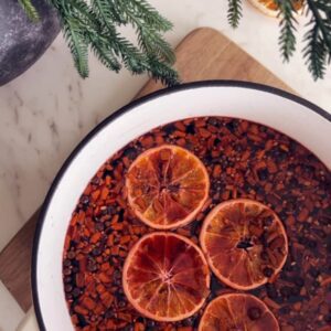 Glasses of warm mulled wine garnished with orange slices and cinnamon sticks ready for serving