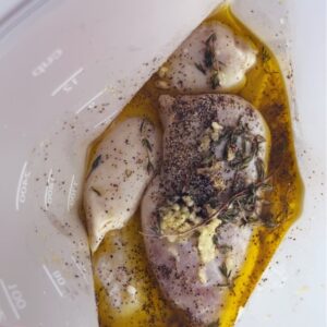 Lemon herb Dijon chicken marinade in freezer bag with fresh lemon zest and herbs visible