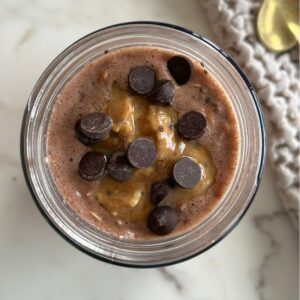 Mason jar filled with Peanut Butter Cup overnight oats with dark chocolate color and chocolate chips visible on top.