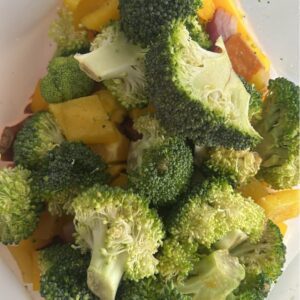 Reusable freezer bag with layered sausage bowl ingredients: gluten-free chicken sausages, diced sweet potatoes, bell peppers, broccoli, red onion, and Dijon honey mustard dressing