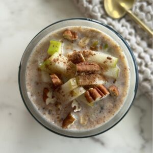 Mason jar filled with Apple Pie overnight oats topped with chopped apple pieces and pecans.